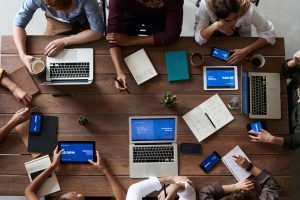 business professionals brainstorm around table with laptops