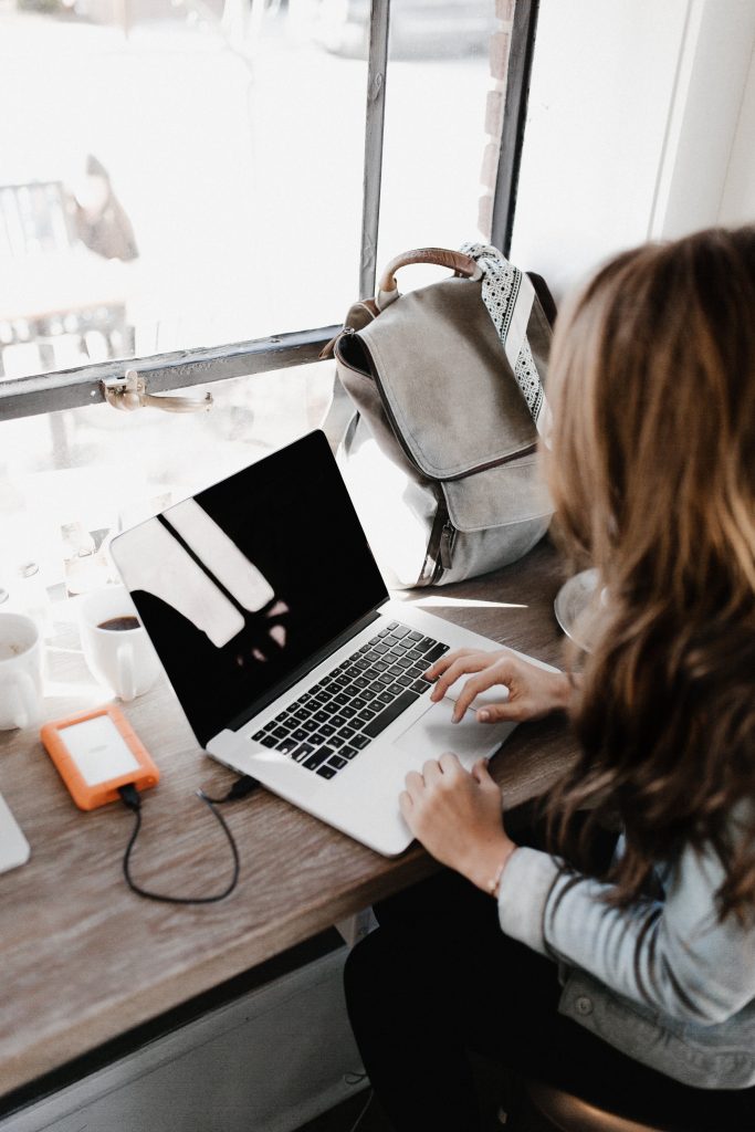 woman sitting at table with hard drive and lapto[