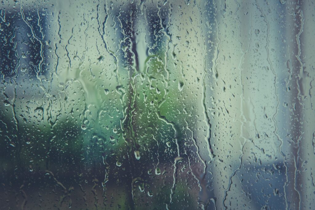 Darkened Window on Rainy Day With Rivulets of Rain in Focus