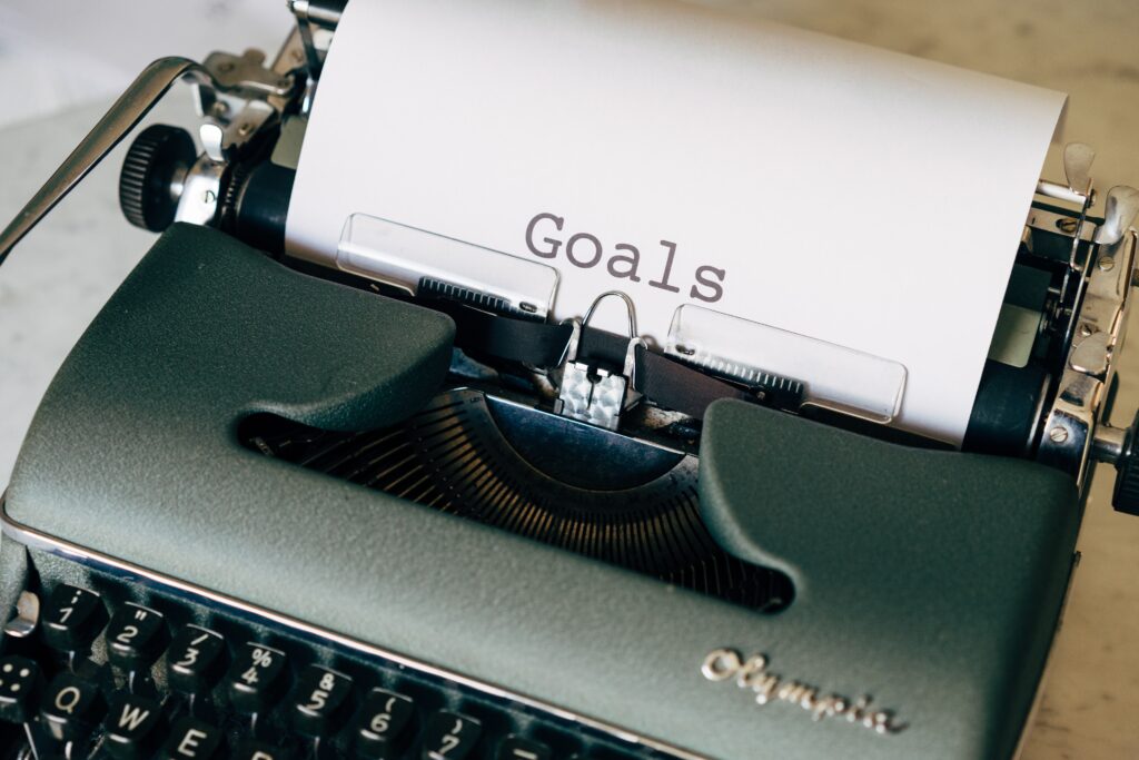 Green Typewriter on Brown Wooden Table with Goals Written on the Page