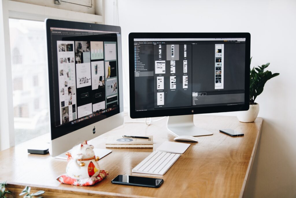 Two Imac's With Keyboard and Phones on Desk