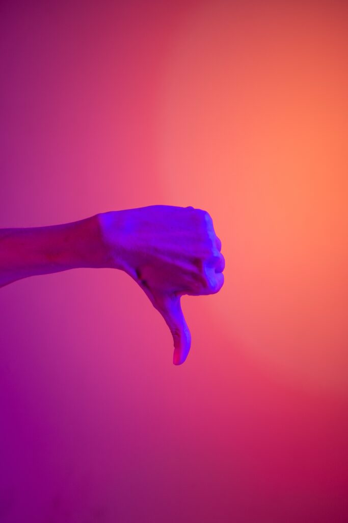 Image of person giving thumbs down against colorful red background