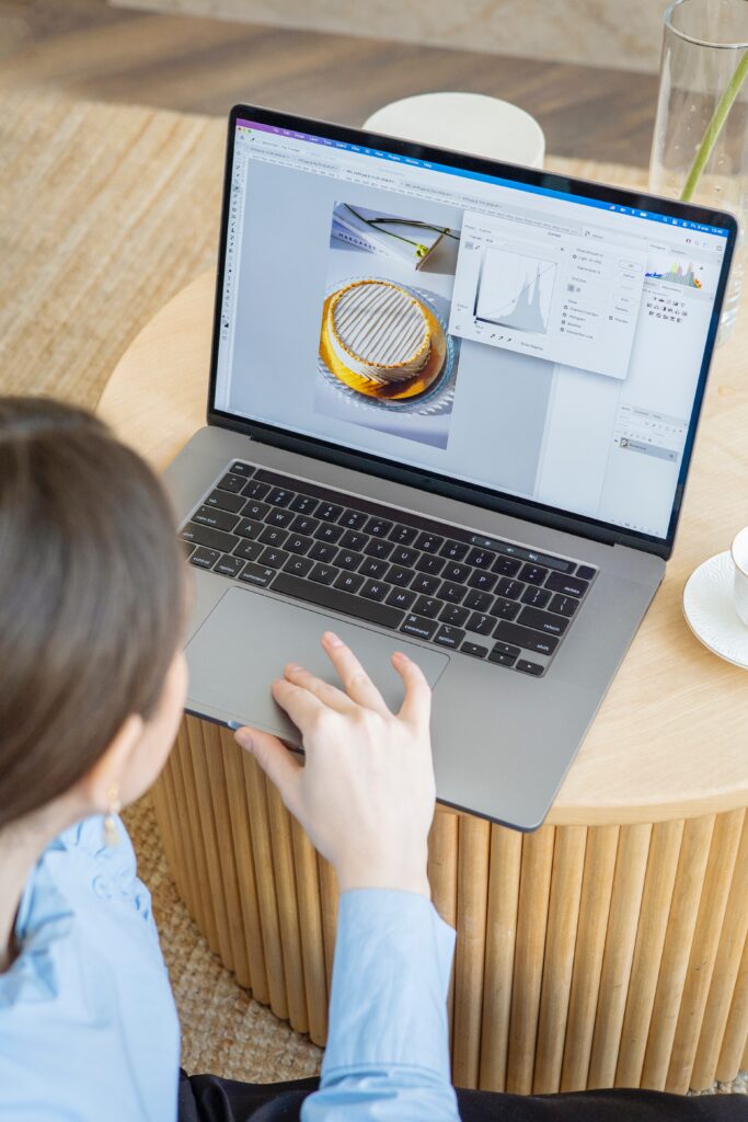 Woman in White Long Sleeve Shirt Using Macbook Pro to Edit Photo